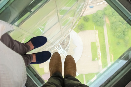 Male and female feet on a glass floor at the Ostankino tower in Moscow, Russiaの写真素材