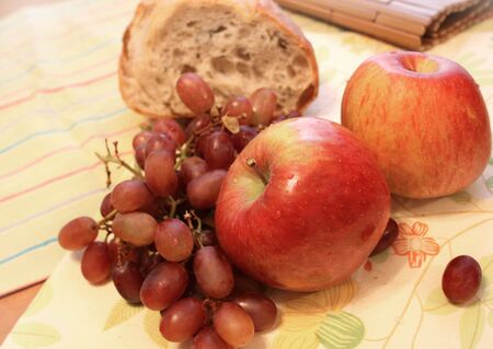 View of apples, grapes and bread on a tableの写真素材