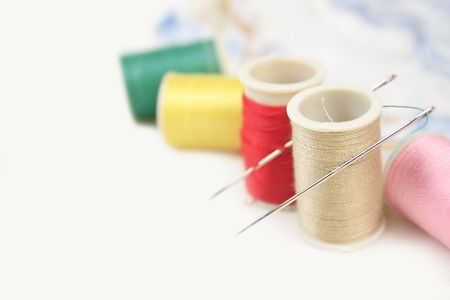 Versatile craft, sewing background: threads and needles on white 