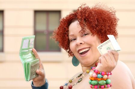 Plus size female model with red curly hair, colorful jewelry and a wallet, holding money (five dollar bill)の写真素材