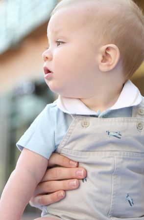 Adorable baby boy with blue eyes held by his momの写真素材