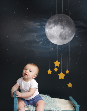 Baby sitting in bed, looking at the moon and stars mobile, starry night  Nap time, sleeping conceptの写真素材