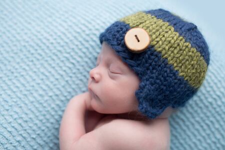 Sleeping newborn baby boy, infant, on a blue knit blanket, posed asleep during nap time