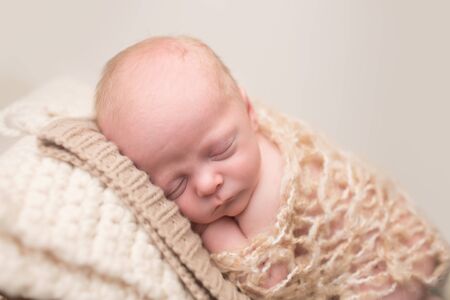Newborn Baby Asleep, sleeping and taking a nap on a textured blanket posed and curled upの写真素材