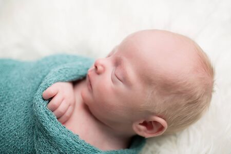 Newborn Baby swaddled, sleeping or napping, on soft white furの写真素材