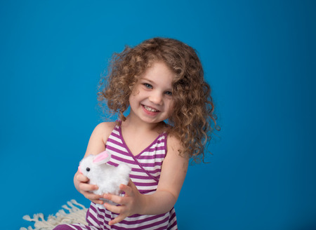 Happy, laughing smiling child, girl, playing with easter bunny, looking at cameraの写真素材