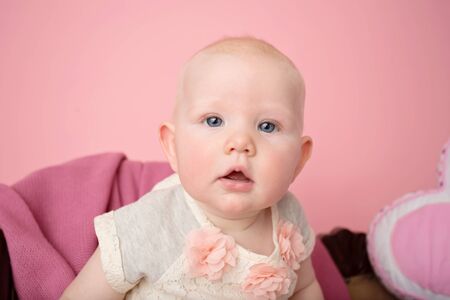 Adorable baby girl sitting looking at the camera, child development milestoneの写真素材