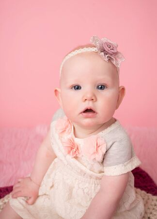 Adorable baby girl sitting looking at the camera, child development milestoneの写真素材