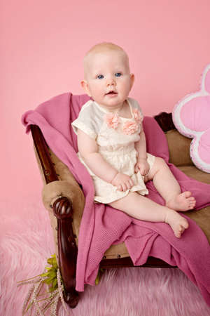 Baby sitting on couch with blanket, baby room and furniture conceptの写真素材