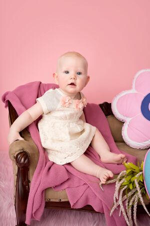 Baby sitting on couch with blanket, baby room and furniture conceptの写真素材