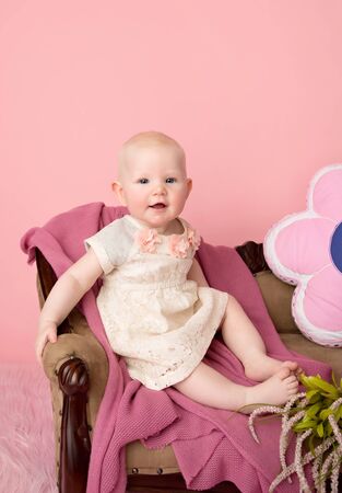 Baby sitting on couch with blanket, baby room and furniture conceptの写真素材