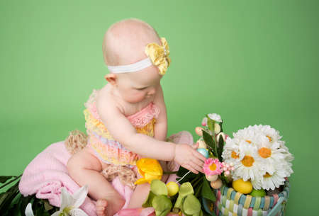 Baby girl on pink background holding an easter eggの写真素材