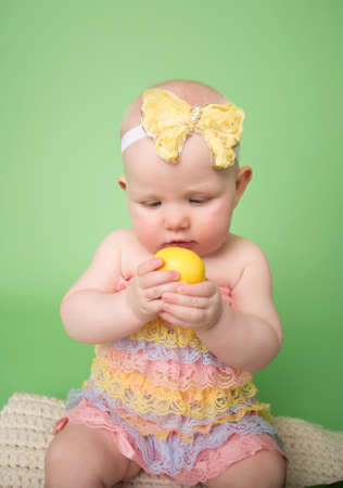 Baby girl on pink background holding an easter eggの写真素材