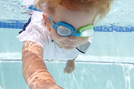 Child, kid, diving and swimming in pool underwater, summer or sports themeの写真素材