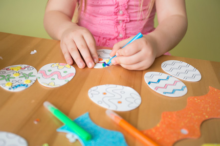 Child doing Easter activities and crafts with bunny stickers, Easter Egg shapes, pencils and markers.の写真素材