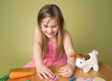 Child doing Easter activities and crafts with bunny stickers, Easter Egg shapes, pencils and markers.の写真素材