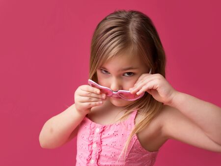 Serious girl in pink sunglasses looking at cameraの写真素材