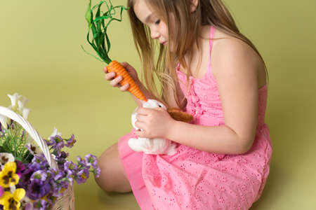 Happy smiling girl feeding a carrot to the Easter Bunnyの写真素材