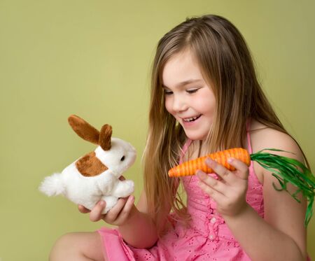 Happy smiling girl feeding a carrot to the Easter Bunnyの写真素材