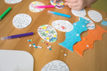 Child doing Easter activities and crafts with bunny stickers, Easter Egg shapes, pencils and markers.の写真素材