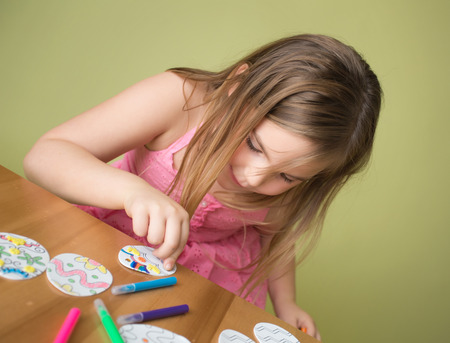 Child doing Easter activities and crafts with bunny stickers, Easter Egg shapes, pencils and markers.の写真素材