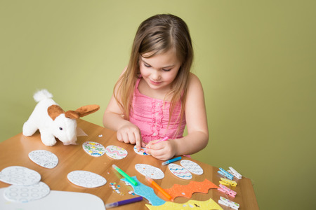 Child doing Easter activities and crafts with bunny stickers, Easter Egg shapes, pencils and markers.の写真素材