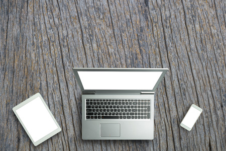 Top view of digital laptop computor, tablet and smartphone white screen on wooden table background.Copy spaceの写真素材