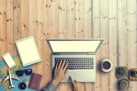 Concept of hipster travel traveler travelling and shopping. Hat, Sun Glass, Smartphone, tablet, compass, bag, map, Cup of Coffee and passport on wooden table background.Copy Space and Vintage toneの写真素材