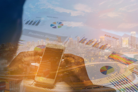 Double exposure of business concept.Business people hands working with smartphone and business document.With Sunset scene of Bangkok cityscape with  Traffic on the freeway in the business district. の写真素材