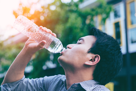 Handsome asian businessman in casual cloth drinking water from a bottle in parkの写真素材