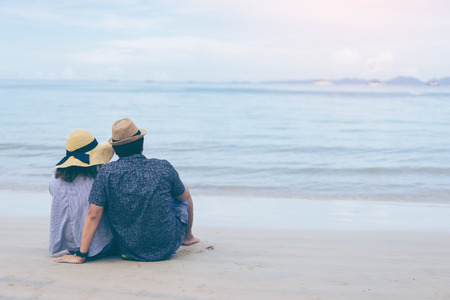 Young couple traveler on a tropical beach at Railay beach Krabi Thailand, Love couple traveler sitting on beach rear viewの写真素材