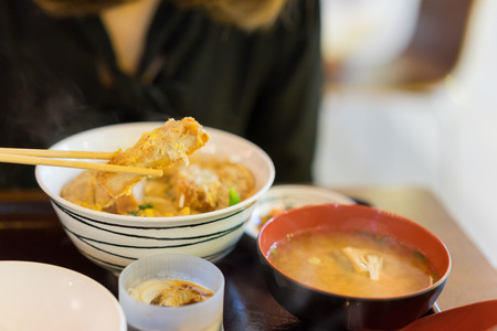 Woman hands eating katsudon or tonkatsu set with miso soup in bowl on restaurantの写真素材