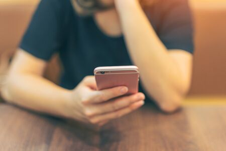 Woman hand using smartphone at cafeteria. Young female using smart phone at restaurant.