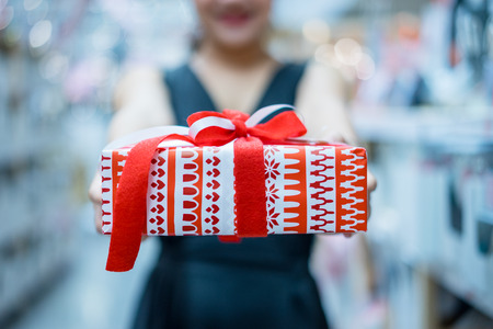 Portrait of smiling young asian woman give a gift to you at Christmas fair or new year.の写真素材