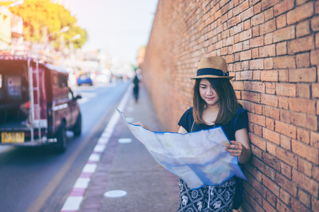 Young asian woman traveler with hat and bag looking map at Tha Pae Gate at the old Chiangmai city in Chang Mai, Thailand.のeditorial素材