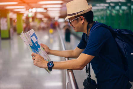 Young man asian traveler looking map at Hong Kong subway station MTRの写真素材