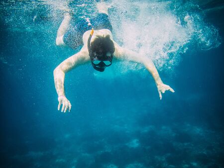 Underwater view of a young diver man swimming under blue sea under the surface with snorkelling mask...