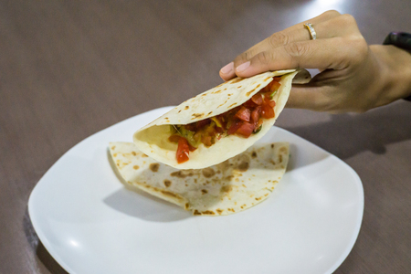 Taco dish on table and in female handの写真素材