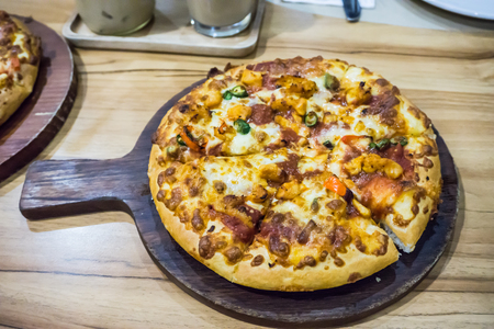 Hot baked Pizza ready to eat serve on wooden board on tableの写真素材
