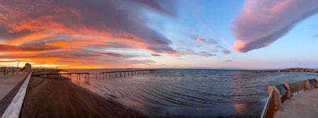Huge colourful panoramic view at sunrise of the Costanera walkway with red and orange lenticular clouds in Punta Arenas, Chileの写真素材