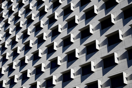 Horizontal color image of a facade of a modern multi-storey residential building wall with symmetrical windowsの写真素材