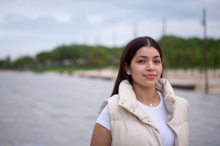 A young woman is posing gracefully at a picturesque waterfront, reflecting elegance and beautyの写真素材
