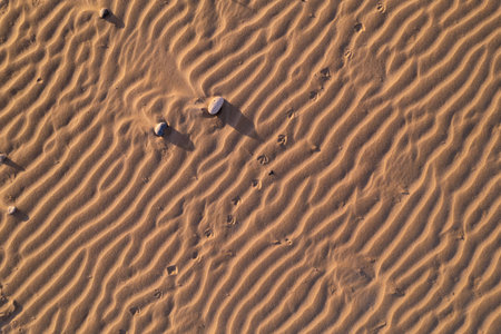 Top view Close-up image of small sand dunes pattern with some small stones, relaxing background