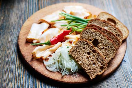 cutting lard with onions, black bread and hot peppers on old wooden table. Traditional Russian appetizer.の写真素材