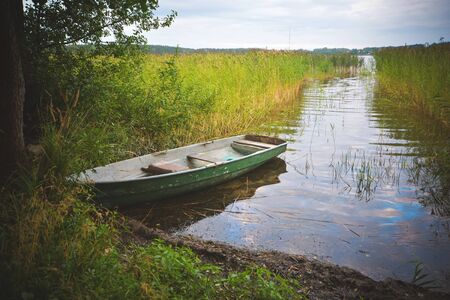Fishing boat in a calm lake water. Old wooden fishing boat in a still lake water.