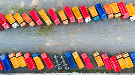 Aerial view of multi-colored dump trucks, trailers, trucks and chassis in the Parking lot for new cars. Factory for the production of heavy-duty vehicles. Top view.の写真素材