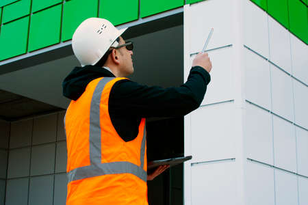 Builder inspects the new building, writing down comments in the tablet.. Building inspector....