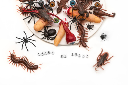Trick or treat words surrounded by candy bugs, joke plastic fingers and eyeballs on an overflowing...