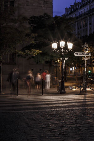 Shadowy and blurred men and women on zebra crossing at night on an urban street.の写真素材