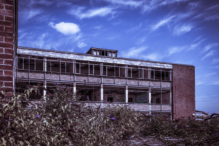 Red brick and concrete office building with no windows. Abandoned and derelict under a blue skyのeditorial素材